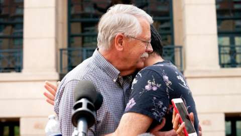 Carl Mueller, father of late US aid worker Kayla Mueller, hugs her friend after a jury convicted El Shafee Elsheikh on terrorism charges