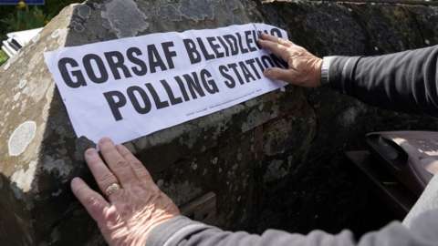 An administrator fixes a sign outside a polling station