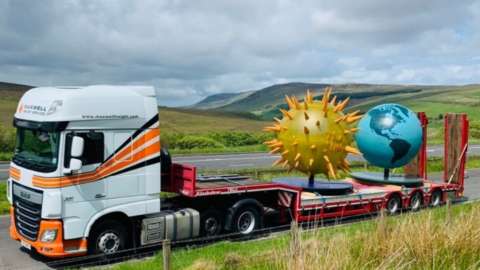 Truck with sun and earth on back of lorry