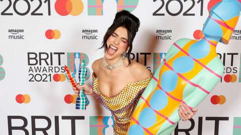 Dua Lipa holding her two Brit Awards
