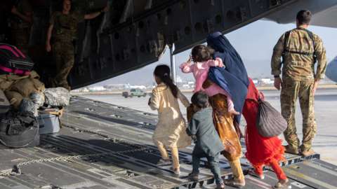 A mother and her children board a US air force C-17 plane at Kabul Airport