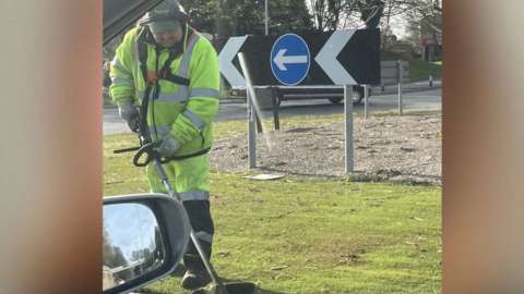 The council worker strimming the plastic grass