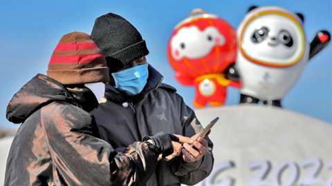 People check photos on mobile phone near the Bing Dwen Dwen (R), the Beijing 2022 Winter Olympic Mascot and Shuey Rhon Rhon, the 2022 Beijing Winter Paralympic Games Mascot