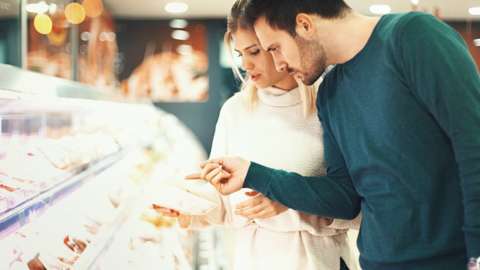 People looking at supermarket meat counter