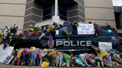 Police car covered in flowers in tribute to police officer Eric Talley and the other victims of the mass shooting in Boulder on Monday