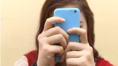 Teenager on a phone obscuring her face