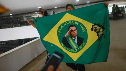 A supporter of Brazil's former President Jair Bolsonaro holds a flag depicting him during a demonstration against President Luiz Inacio Lula da Silva, in Brasilia, Brazil, January 8, 2023.