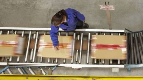 A worker scanning boxes on a conveyor belt