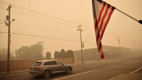A car and a US flag in the smoke-filled town of Molalla, Oregon
