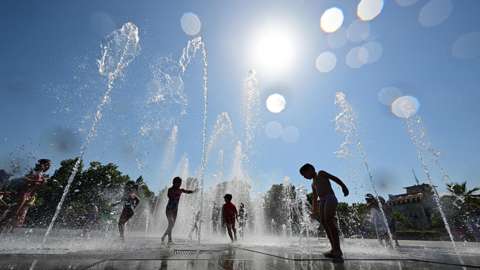 Children play in fountain on sunny day