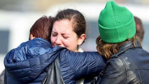 Women react as they embrace each other after the attack