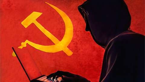 The old Communist Russian hammer and sickle is seen in the background of a silhouetted "hacker" caricature wearing a hoodie