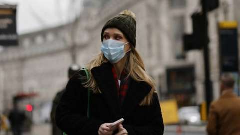 A woman wearing a face mask walks in London on January 21, 2022