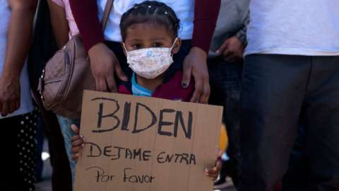 Dareli Matamoros, a girl from Honduras, holds a sign asking President Biden to let her in during a migrant demonstration demanding clearer United States migration policies, at San Ysidro crossing port in Tijuana, Baja California state, Mexico on March 2, 2021
