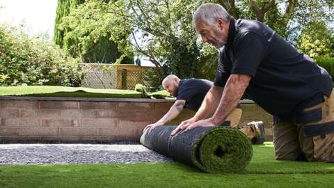 Fitters install a new plastic lawn
