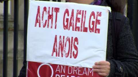 Demonstrator with sign calling for Irish language legislation.