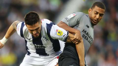 Okay Yokuslu (left) of West Bromwich Albion is challenged by Andy Rinomhota of Cardiff City