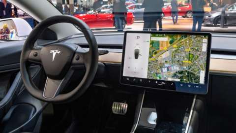 The interior of the Tesla Model 3, shown with a large tablet-like device mounted in the central console to the side of the steering wheel