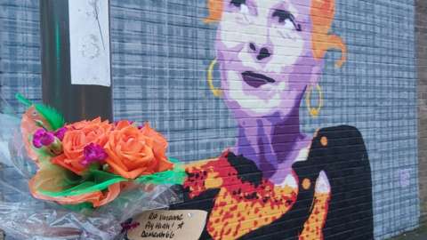 Flowers left by the mural to Vivienne Westwood