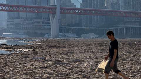 A man walks on the dried out riverbed of the Jialing River, a major tributary of the Yangtze River, in Chongqing, China, 21 August 2022