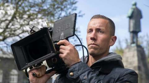 Hannes Halldorsson holds camera.