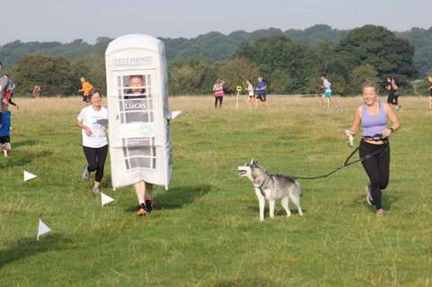 man running in phonebox costume