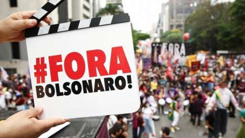 A demonstrator holds a sign that says 'Bolsonaro out'
