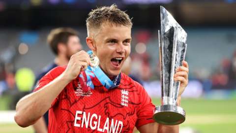 Sam Curran smiling while holding the T20 World Cup and player of the match medal
