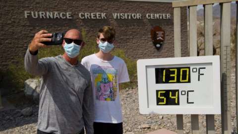 Tourists on a road trip from Texas, take pictures with a thermometer displaying temperatures of 130 Degrees Fahrenheit (54 Degrees Celsius) at the Furnace Creek Visitor's Center at Death Valley National Park