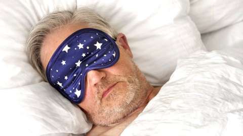 Man in bed wearing an eye mask