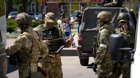 Russian servicemen patrol a street in Melitopol, 1 May 2022
