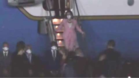 Nancy Pelosi in pink suit walking down stairs off airplane