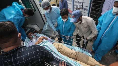 Health workers move a suspected COVID-19 patient outside the Vijay Vallabh COVID care hospital in the aftermath of a fire