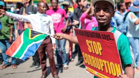 A demonstrator holds a placard reading "Stop corruption" as members of Save SA organisation