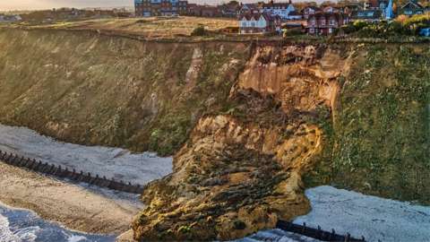 A drone operator describes a cliff collapse on to a beach as "disproportionately massive".