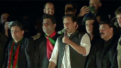 Imran Khan speaking to the crowd, surrounded by supporters