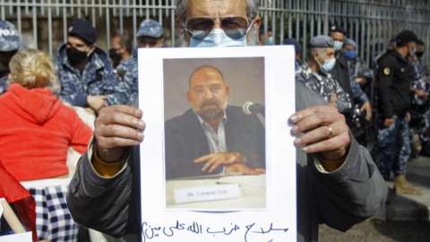 People holding photographs of Lokman Slim protest outside the Palais de Justice in Beirut, Lebanon