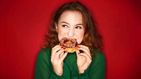 A young woman chews on a doughnut
