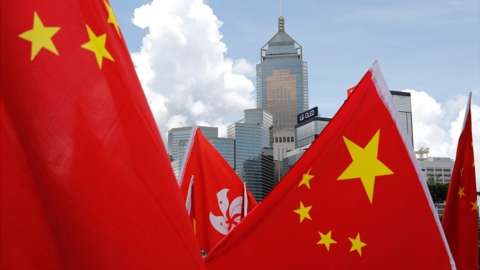 Buildings are seen above Hong Kong and Chinese flags, as pro-China supporters celebration after China's parliament passes national security law for Hong Kong, in Hong Kong, on 30 June 2020