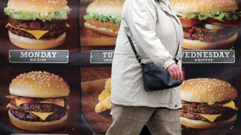 A person walking past an advert for hamburgers