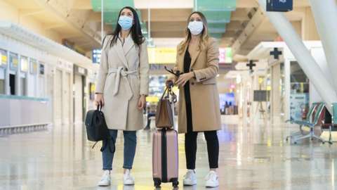 Two women standing at an airport