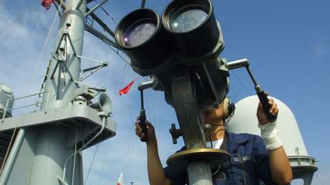 A U.S. Navy sailor looks out through binoculars from aboard the USS Mount Whitney February 26, 2003 in the Gulf of Aden off the coast of Djibouti.