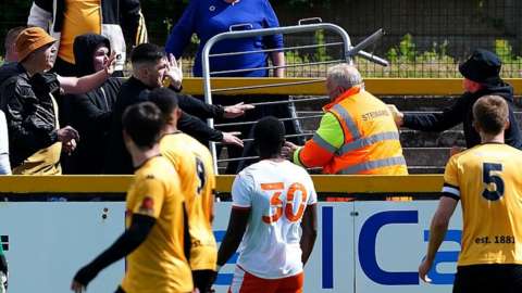 Blackpool and Southport fans clash in the stands as the referee is forced to take the players off the pitch during the pre-season friendly match at The Pure Stadium, Southport