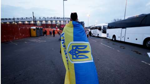 A fan with a flag for Ukraine in support of Ukraine amid Russia's invasion outside the stadium before the match