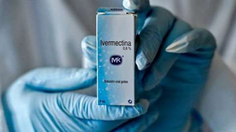 A health worker shows a box containing a bottle of Ivermectin