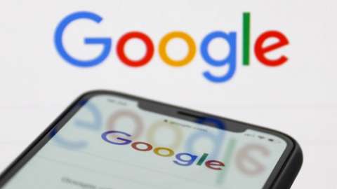 Google Search displayed on a smartphone against a Google logo background