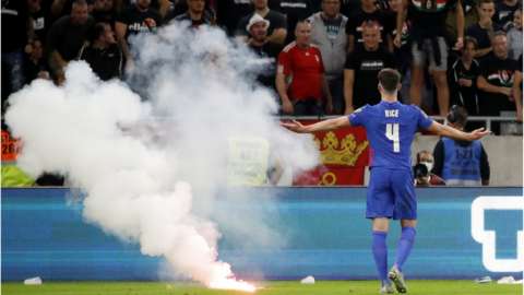 Hungary fans throw a flare on the pitch in front of England players