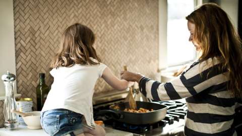 Stock photo of a mother and daughter cooking on a gas cooker