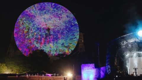 The Lovell radio telescope at Jodrell Bank lit with scientific data for the Bluedot festival