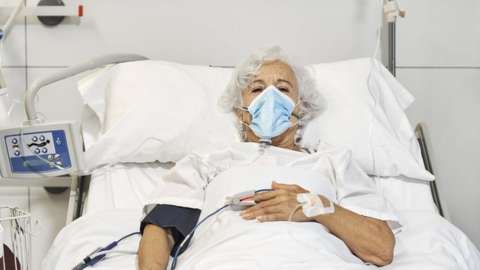Woman in face mask in hospital bed (file image)